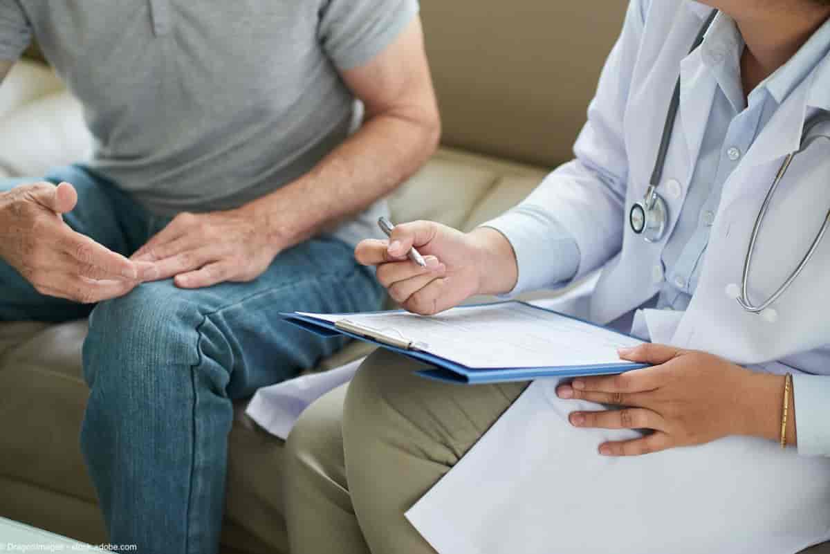 Crop shot of senior man sitting on sofa with doctor during home visit taking notes on clipboard | Image Credit: © DragonImages - stock.adobe.com